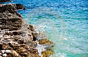 Rocky coast with splash water in front of blue sea