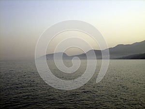 Rocky coast at sunset. In the distance, the coast mountains loomed in the mist