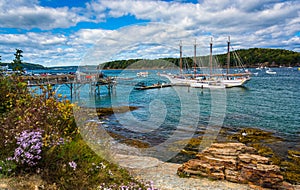 Rocky coast and view of boats in the harbor at Bar Harbor, Maine photo