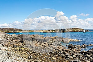 Rocky coastal beach in Inishbofin with CromwellÃ¢â¬â¢s Barracks and a sailing ship in de background photo