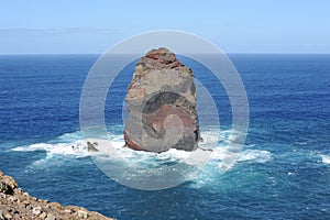 Rocky coastline of the Atlantic Ocean with waves and cliffs mountains and blue sky in Madeira Island, Portugal
