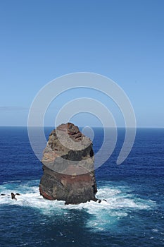 Rocky coastline of the Atlantic Ocean with waves and cliffs mountains and blue sky in Madeira Island, Portugal