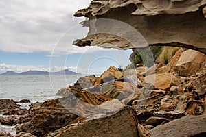 Rocky coastline with blue sea and an island on background, Auckland, New Zealand