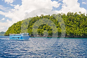 Rocky coastline of island spotted by islets and covered by dense lush green jungle in the colorful sea of the remote Togean Island