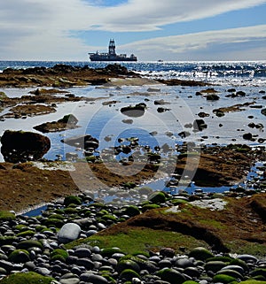 Rocky coastline at low tide and oil rig