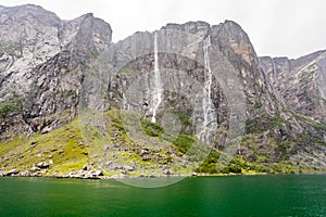 Rocky coastline of Lysefjord with cliffs, waterfalls and green water lagoon, Forsand municipality, Rogaland county, Norway