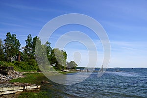 Rocky coastline with pier in distance and green trees