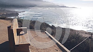 Rocky craggy ocean beach, Point Lobos, California coast. Empty bench on trail.
