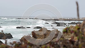 Rocky craggy ocean coast, sea water waves crashing on rocks, Monterey California