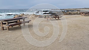 Rocky craggy ocean coast, sea waves, Monterey California. Wooden empty bench.