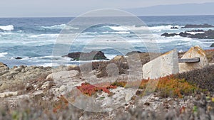 Rocky craggy ocean coast, sea waves, Monterey California. Wooden empty bench.