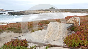 Rocky craggy ocean coast, sea waves, Monterey California. Wooden empty bench.