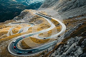 A rocky and curvy road winds through the mountains, surrounded by untamed wilderness, Cars winding their way up a mountain pass -