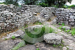 A rocky field with a few trees and a cloudy sky An ancient stone gate building in the nature reserve Nuraghe-Mannu Archaeological photo
