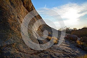 Rocky foothills of a mountain in an arid area with growing grass and boulders under a blue sky. Desert landscape and nature