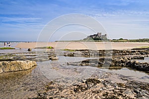 The rocky foreshore and sandy beach with Bamburgh Castle in the background photo