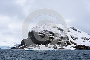 Rocky frozen landscape of Cuverville Island on a stormy day, Southern Ocean, Antarctica