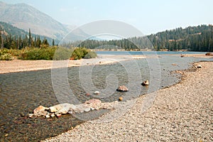 Rocky and gravelly shoreline of Upper Two Medicines Lake in Glacier National Park during the 2017 fall forest fires in Montana USA