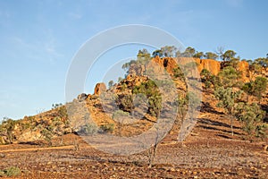 A rocky outcrop hill with sparse trees in outback country, Australia.