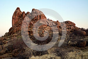 A rocky hill in a rocky arid terrain under a blue sky. Desert landscape and nature