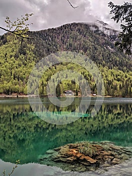 Rocky island in aquamarine mirroring lake among mountains and woods