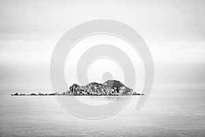 Rocky island in the ocean. Black and white image