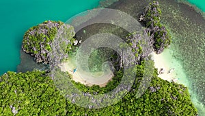 Rocky island with a small white beach, aerial view . Caramoan Islands, Philippines.