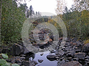 A rocky landscape with trees and rocks in the foreground. Suna River, Poor Porog Waterfall, Girvas, Republic of Karelia, Russia