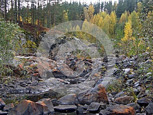 A rocky landscape with trees and rocks in the foreground. Suna River, Poor Porog Waterfall, Girvas, Republic of Karelia, Russia