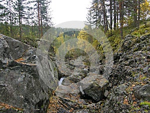 A rocky landscape with trees and rocks in the foreground. Suna River, Poor Porog Waterfall, Girvas, Republic of Karelia, Russia