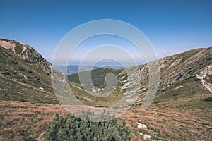 Rocky mountain tops with hiking trails in autumn in Slovakian Tatra western Carpathian with blue sky and late grass on hills.