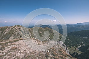 Rocky mountain tops with hiking trails in autumn in Slovakian Tatra western Carpathian with blue sky and late grass on hills.