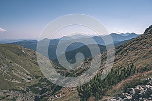 Rocky mountain tops with hiking trails in autumn in Slovakian Tatra western Carpathian with blue sky and late grass on hills.