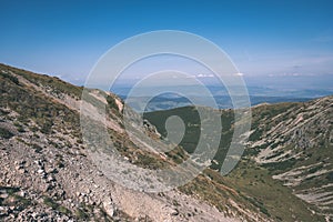 Skalnaté vrcholky hôr s turistickými chodníkmi na jeseň v slovenských Tatrách v západných Karpatoch s modrou oblohou a neskorou trávou na kopcoch.
