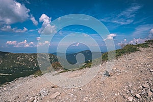 Rocky mountain tops with hiking trails in autumn in Slovakian Tatra western Carpathian with blue sky and late grass on hills.