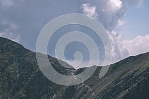 Rocky mountain tops with hiking trails in autumn in Slovakian Tatra western Carpathian with blue sky and late grass on hills.