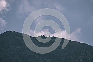 Skalnaté vrcholky hôr s turistickými chodníkmi na jeseň v slovenských Tatrách v západných Karpatoch s modrou oblohou a neskorou trávou na kopcoch.