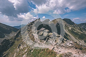 Rocky mountain tops with hiking trails in autumn in Slovakian Tatra western Carpathian with blue sky and late grass on hills.