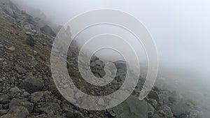 Rocky mountainside in fog. Shot. Top view of rock falls on mountainside. Dense fog envelops rock in autumn cloudy day