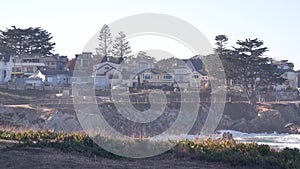 Rocky ocean beach, waves crashing, Monterey, California coast beachfront houses.