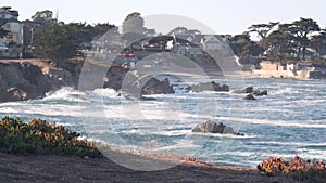 Rocky ocean beach, waves crashing, Monterey, California coast beachfront houses.