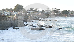 Rocky ocean beach, waves crashing, Monterey, California coast beachfront houses.