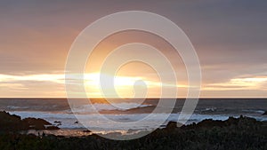 Rocky ocean coast, sea waves, Monterey beach, California, dramatic sunset sky.