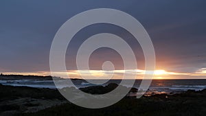 Rocky ocean coast, sea waves, Monterey beach, California, dramatic sunset sky.