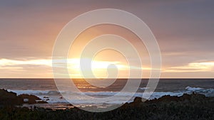 Rocky ocean coast, sea waves, Monterey beach, California, dramatic sunset sky.