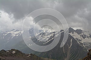 Rocky peaks with snow in the clouds, North Caucasus Elbrus region.