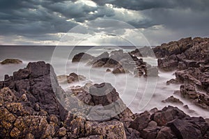 Rocky scottish coastline on a stormy day. Dark clouds and dark rocks looking out to sea