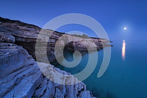 Rocky sea coast and full moon at night in summer