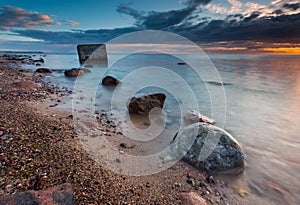 Rocky sea shore with old bunker in sea, long exposure photo