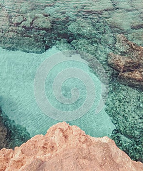 Rocky seabed with blue water and white sand. Mediterranean Sea coast. Lagre stones in the water, vertical top view.
